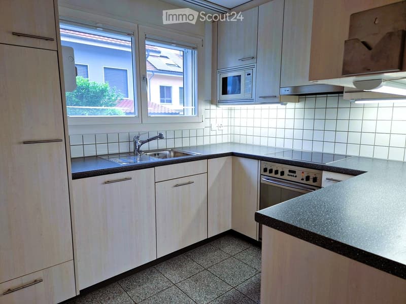 Modern kitchen with white cabinets, stainless steel appliances, and a tiled backsplash. Features a sink, microwave, and oven.