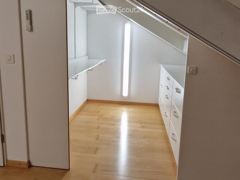 Empty room with wooden flooring, white walls, built-in shelves, and cabinets. No furniture or personal items present.