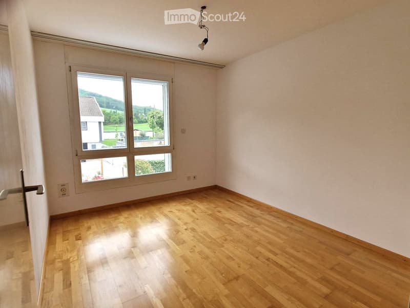 Empty room with wooden flooring, large windows, and white walls. No furniture or equipment present.