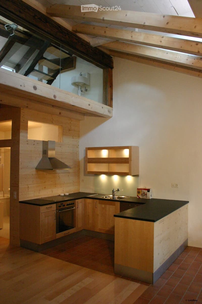 Modern kitchen with wooden cabinets, stainless steel appliances, and a central island. Features include an oven, sink, range hood, and built-in lighting in the cabinets.