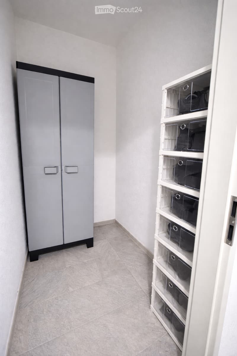 Empty hallway with tiled floor, white walls, and built-in storage units on both sides.