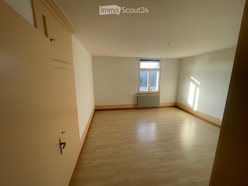 Empty room with wooden flooring, white walls, and a window letting in natural light. No furniture or equipment is present.