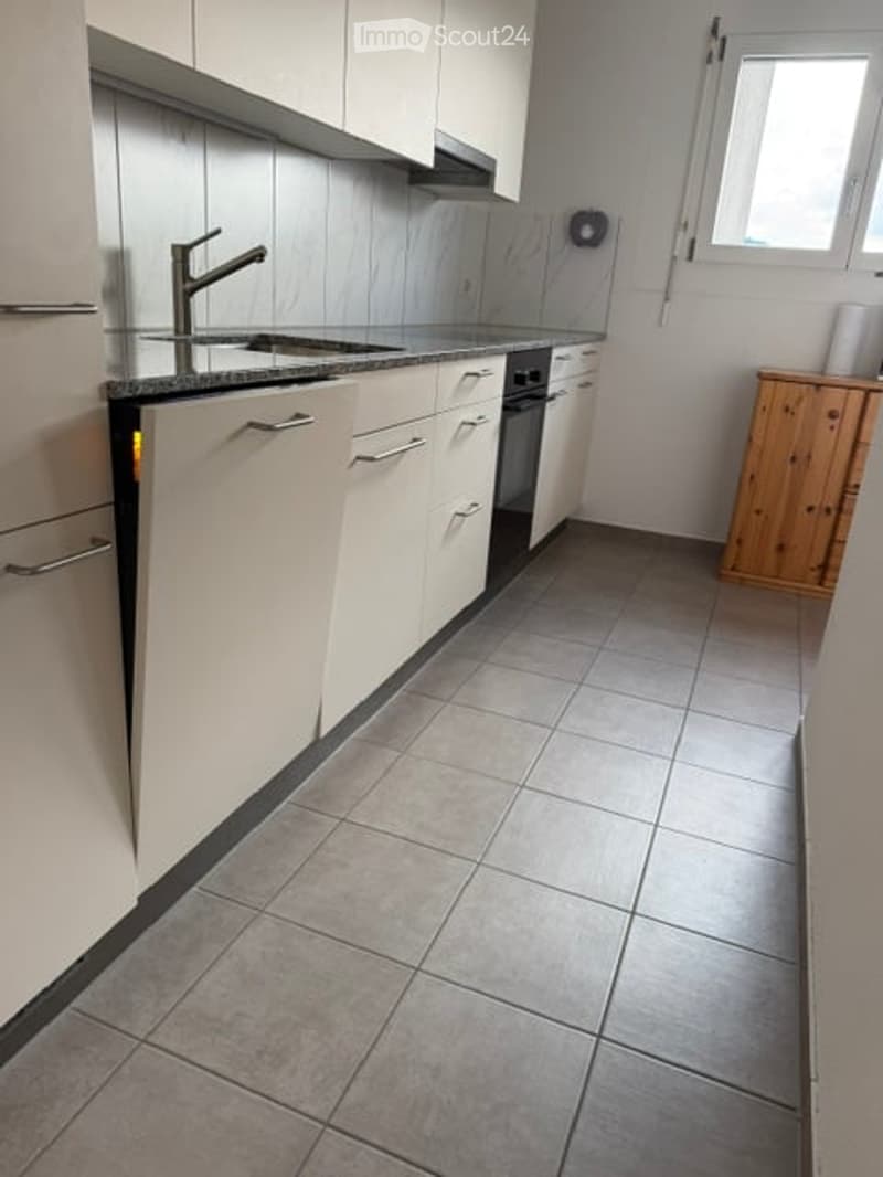 Modern kitchen with white cabinets, stainless steel sink and faucet, tiled floor, and built-in oven and dishwasher.