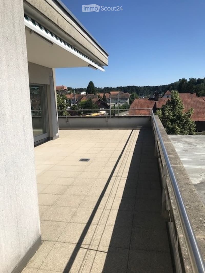 Balcony with tiled floor, metal railing, and a view of a town with houses and trees.