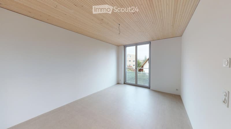 Empty room with white walls, light wooden ceiling, and large sliding glass door leading to a balcony.