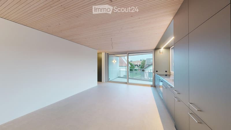 Modern, minimalist room with white walls, light wood ceiling, and grey cabinets. Features a large sliding glass door leading to a balcony.