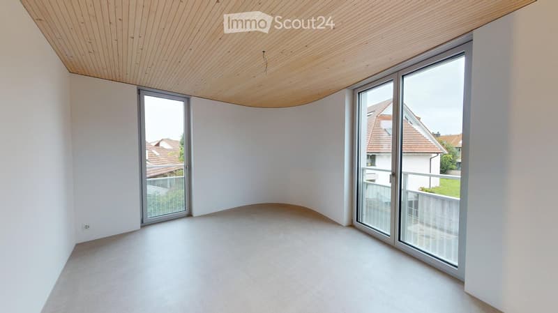 Empty room with white walls, light wooden ceiling, large glass sliding doors leading to a balcony, and a smooth concrete floor.