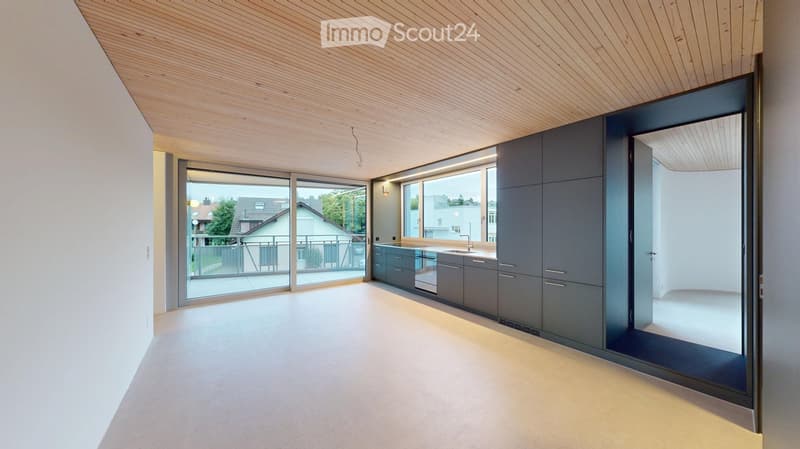 Modern kitchen with grey cabinets, a sink, and large windows opening to a balcony. The space features a sleek, minimalist design with a wooden ceiling and light-colored flooring.