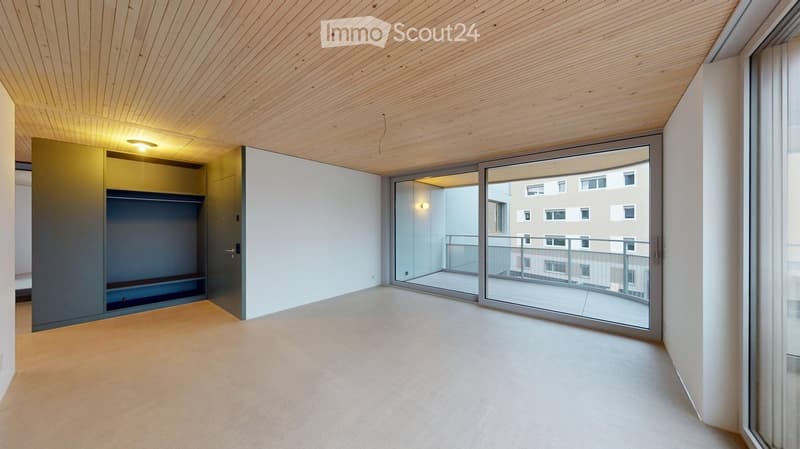 Empty room with light wooden ceiling, white walls, large sliding glass doors leading to a balcony, and a built-in closet with mirrored doors.