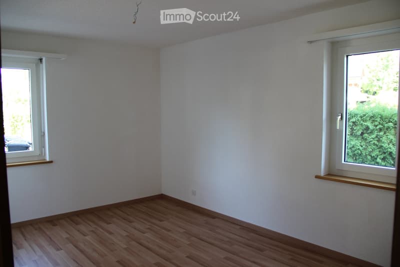 Empty room with wooden flooring, white walls, and two windows with white frames and wooden sills.