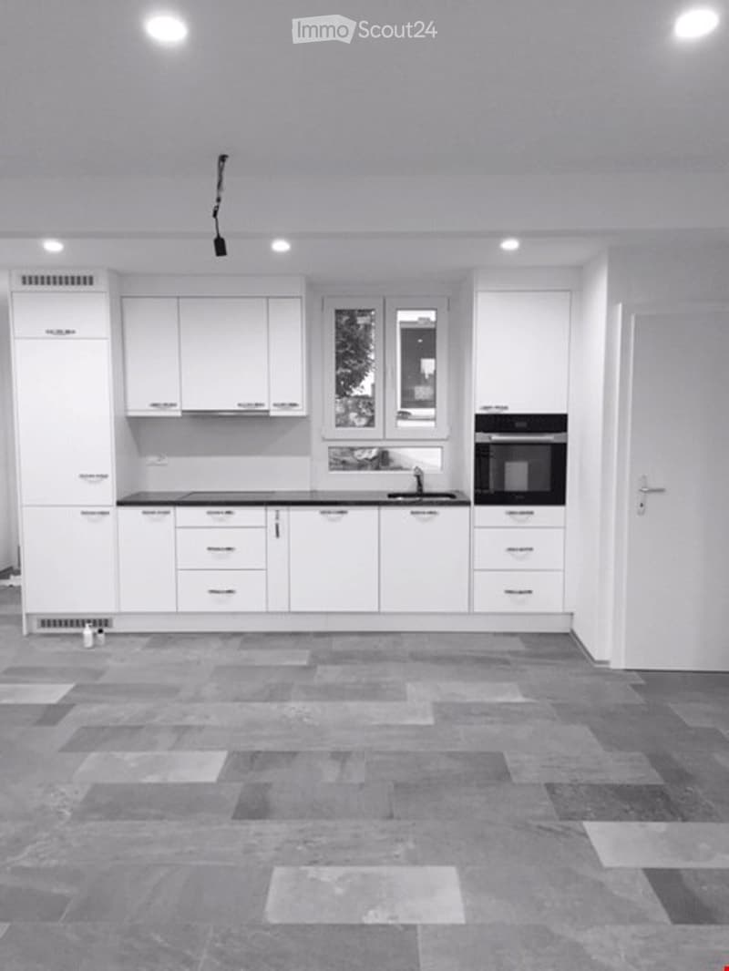 a kitchen with white cabinets, black countertop, and integrated oven