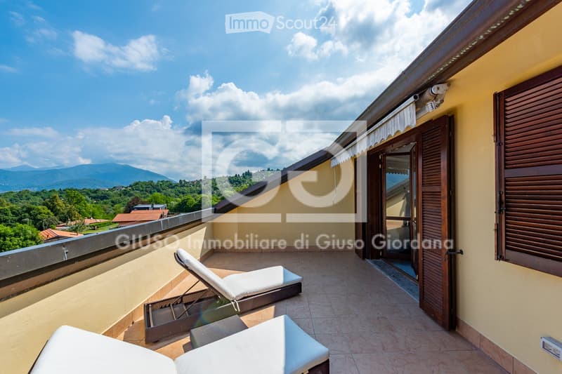 Balcony with sun loungers, a small table, and a scenic view of the countryside and mountains.