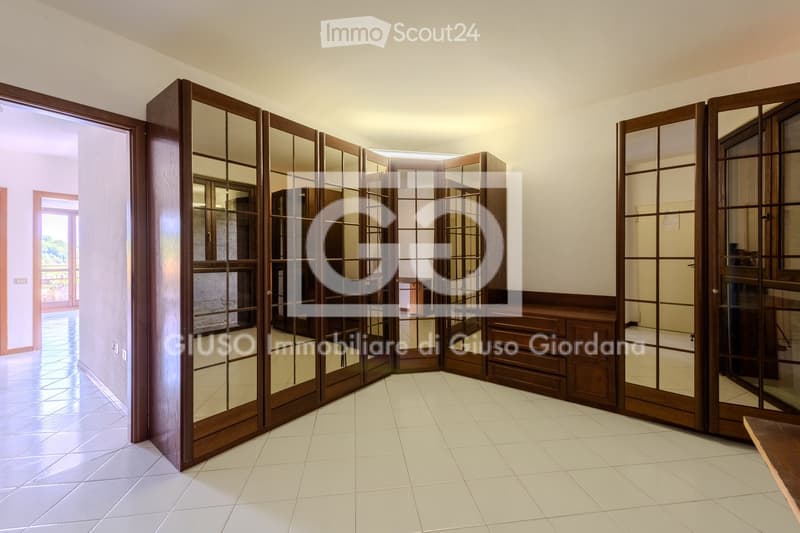 Empty room with white tiled flooring, light-colored walls, and large wooden sliding doors with glass panels.