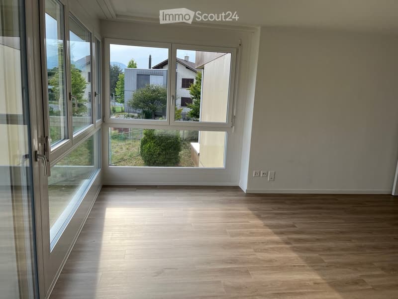 Empty room with wooden flooring, large windows, and white walls.