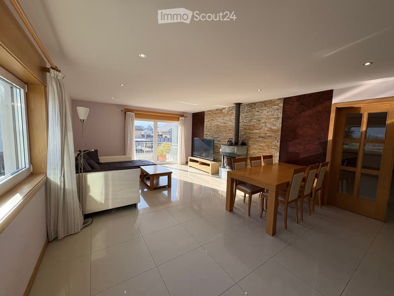 Open-plan living and dining area with a fireplace, sofa, coffee table, dining table, chairs, and television.