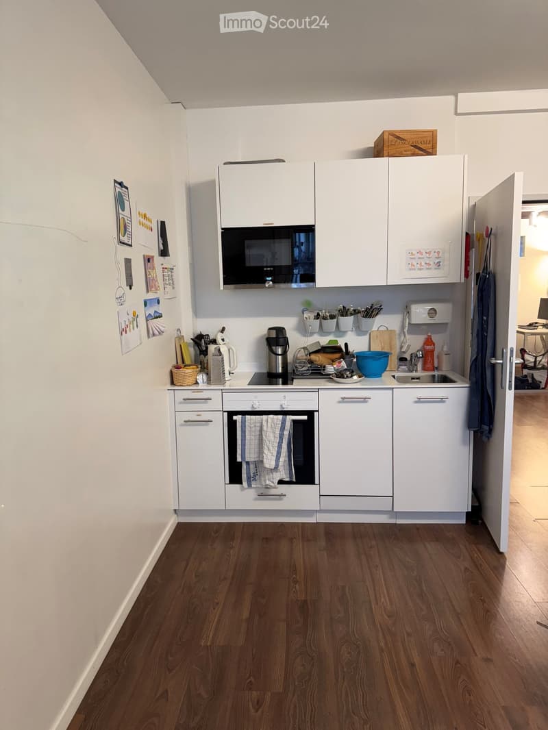 modern kitchen with white cabinets, wooden floor, black stove, microwave, sink, dishwasher, refrigerator, and various kitchen utensils