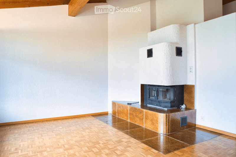 Empty room with wooden flooring, white walls, and a built-in fireplace with a tiled surround.
