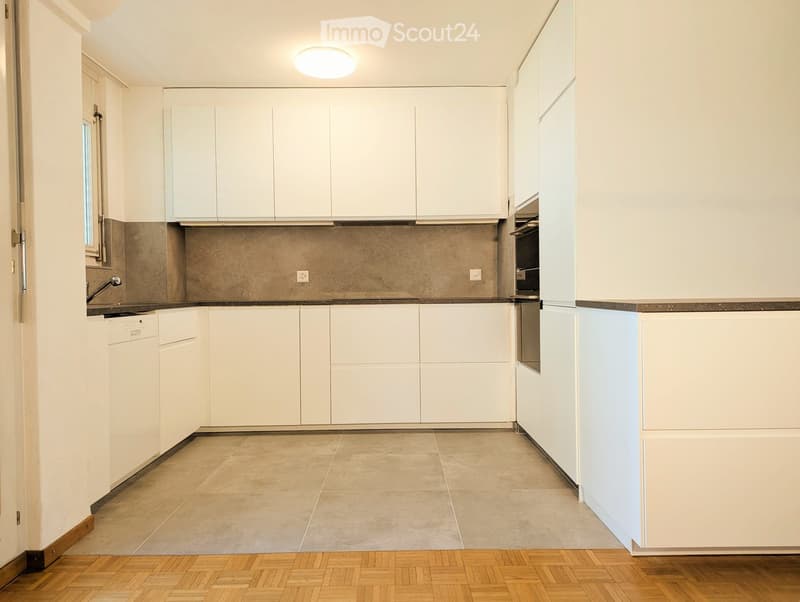 Modern kitchen with white cabinets, stainless steel appliances, and a tiled backsplash.