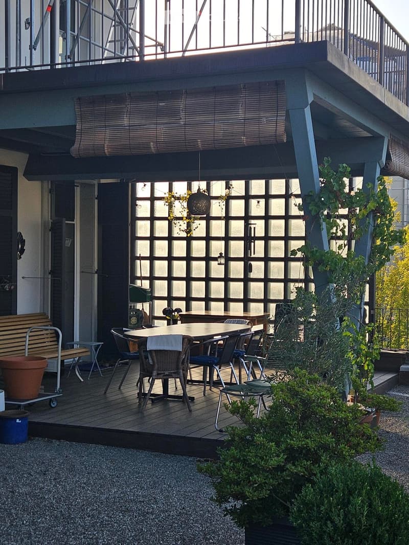 Balcony with wooden decking, table and chairs, bench, and potted plants.