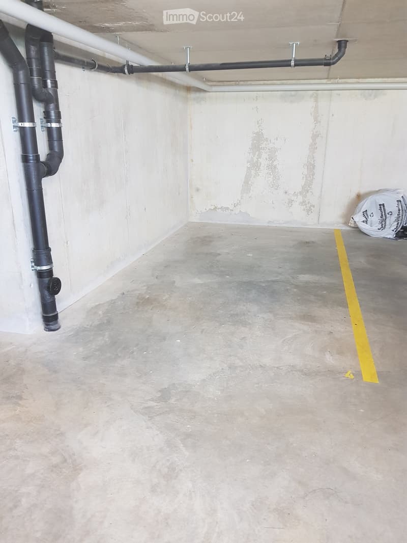 Concrete floor, exposed pipes and ventilation system, yellow parking line on the floor
