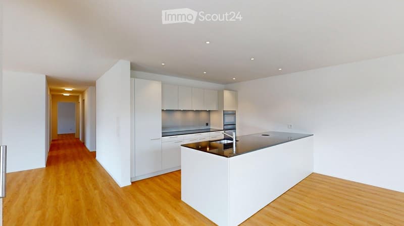 Modern kitchen with white cabinets, a central island, and a stainless steel sink.