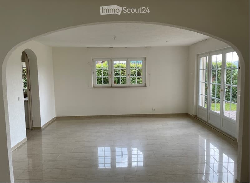 Empty room with white walls, tiled floor, large window, and glass door leading outside.