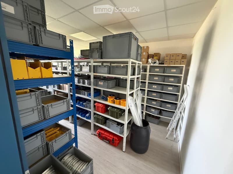 Storage area with multiple shelves filled with gray storage bins, toolboxes, and various items, including buckets and pipes.