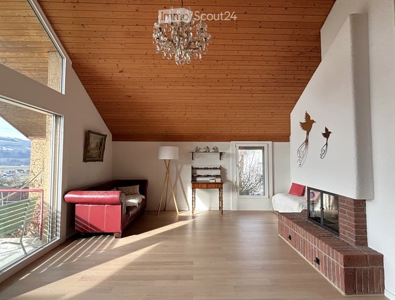 living room, wooden ceiling, chandelier, fireplace, brick wall, large windows, red sofa, standing lamp, desk, shelves