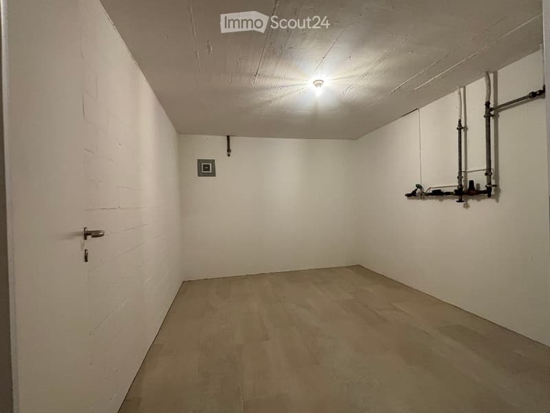 Empty room with white walls, wooden floor, and exposed pipes on one wall. No furniture or equipment present.