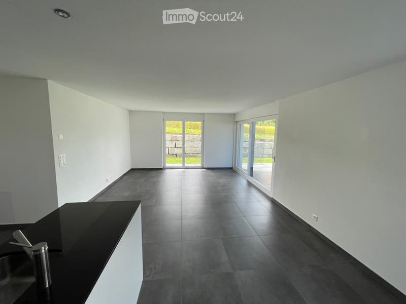 Empty room with grey tiled floor, white walls, and large sliding glass doors leading to an outdoor area.