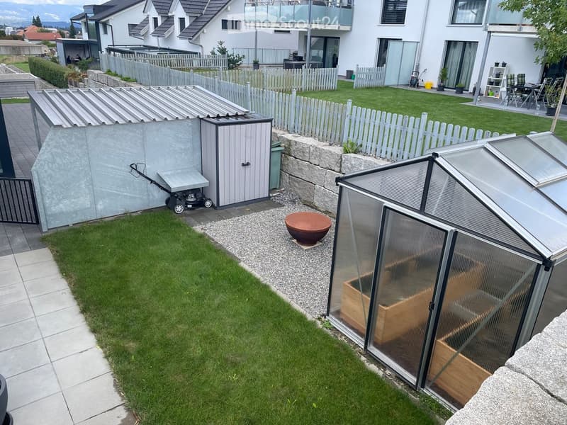 Well-maintained garden with a lawn, greenhouse, shed, patio, and outdoor furniture.