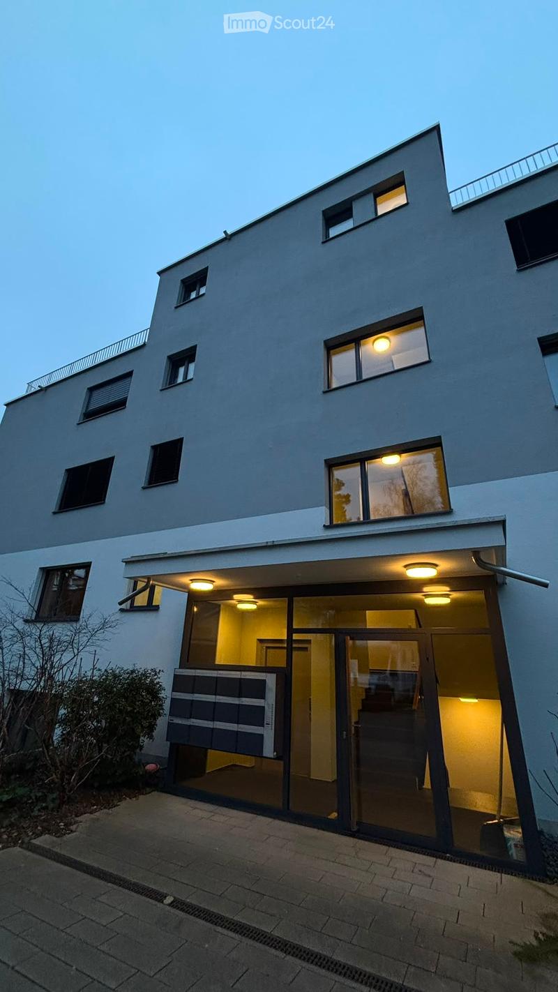 Modern two-story house with large windows, illuminated interior, and a raised ground floor entrance.