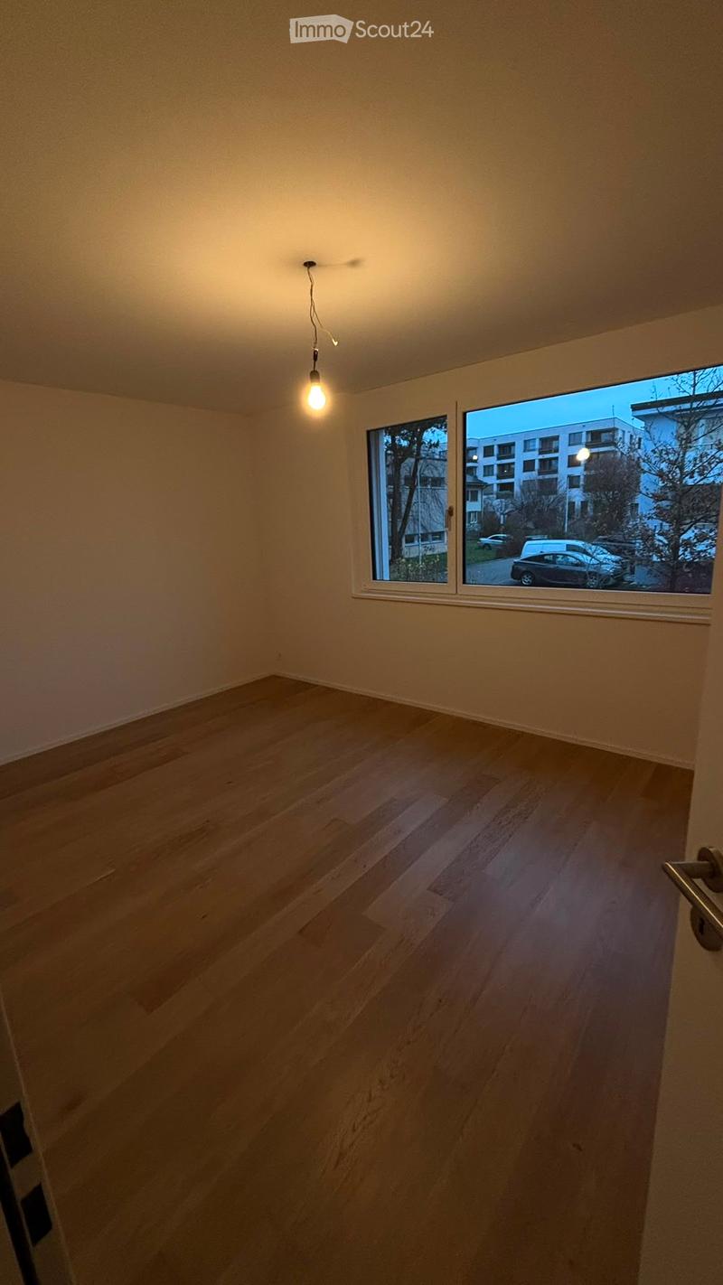 Empty room with wooden flooring, large windows, and a single hanging light fixture.