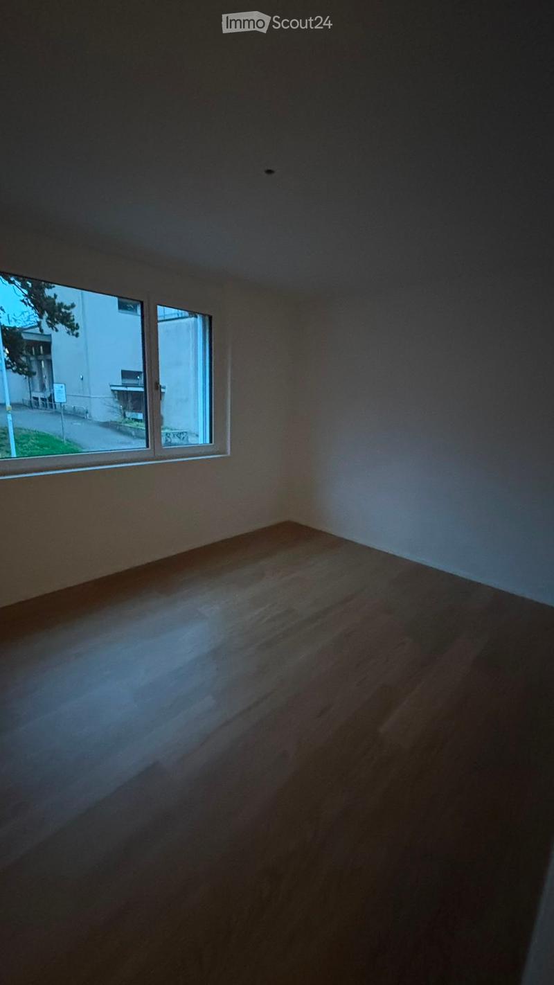 Empty room with wooden flooring and large windows allowing natural light to enter. No furniture or equipment is present.