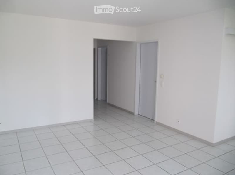 Empty room with white walls and tiled floor, featuring a doorway leading to another room.