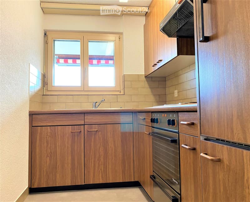 Modern kitchen with wooden cabinets, stainless steel oven, sink, and tiled backsplash.
