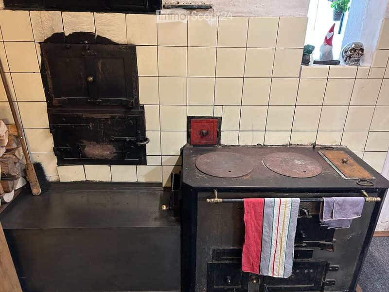 Vintage kitchen with a large black stove, oven, and towel rack with hanging towels.