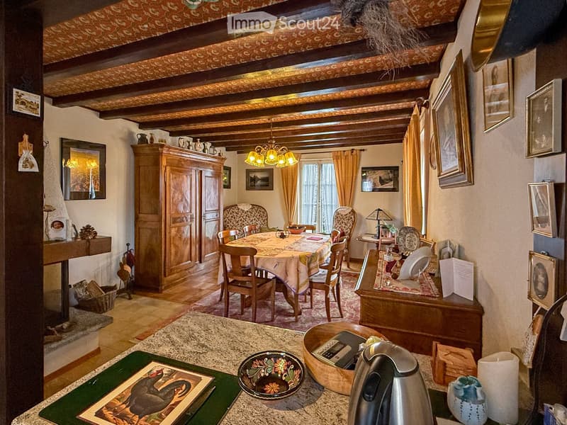 A cozy, rustic dining room with wooden furniture, a chandelier, a fireplace, and a dining table set with chairs.