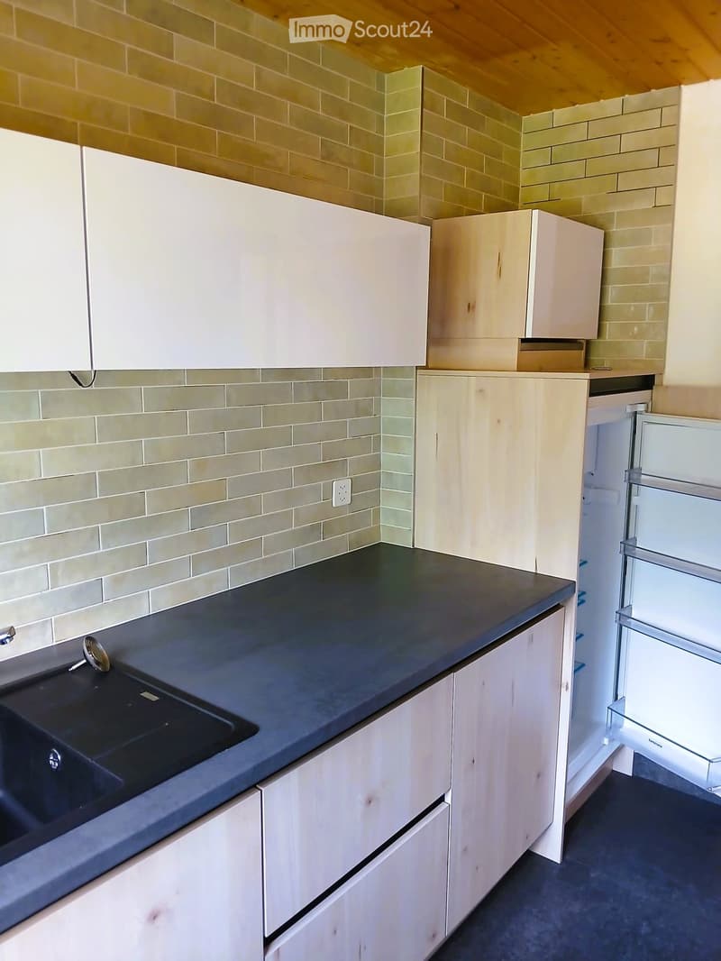 Modern kitchen with white cabinets, dark countertop, and a stainless steel sink.