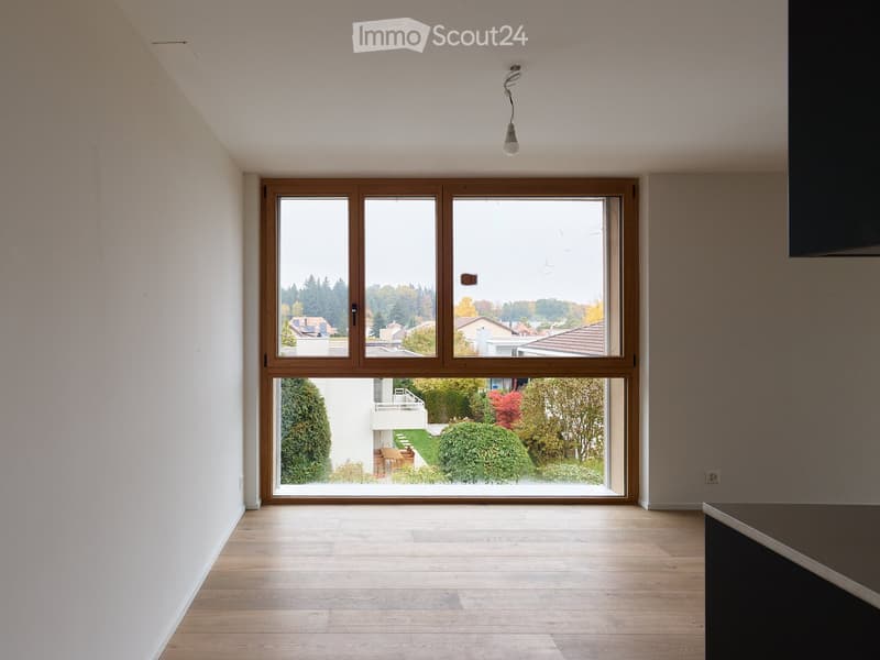 Empty room with wooden flooring, large windows, and white walls. No furniture or equipment visible.