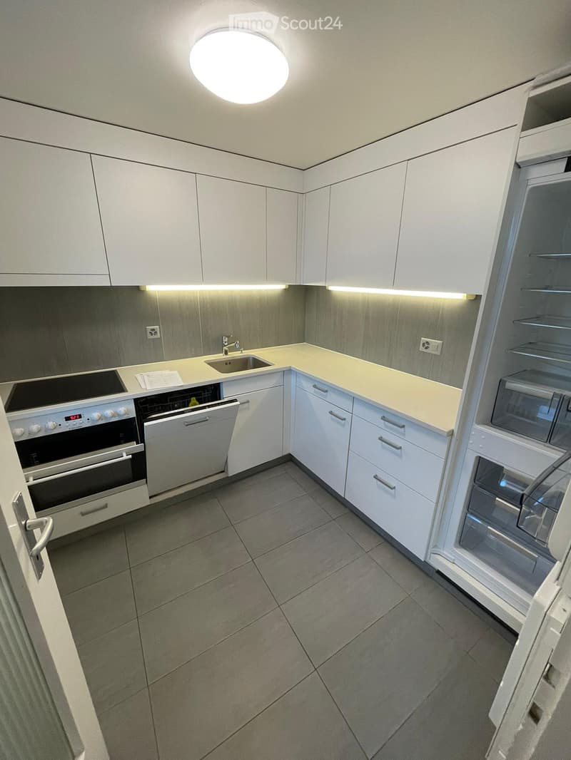 Modern kitchen with white cabinets, stainless steel appliances, and a light-colored countertop.