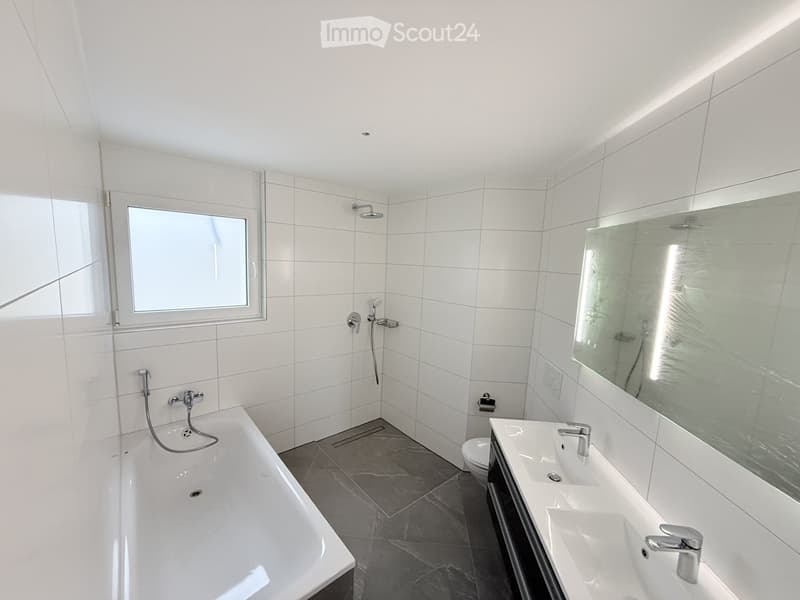 White tiled walls, bathtub, double sink, toilet, mirror, shower head