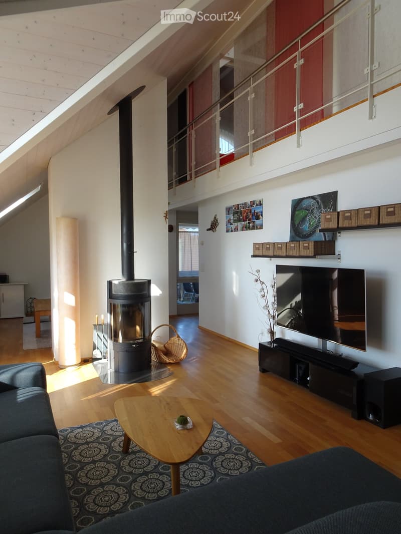 Modern living room with wooden flooring, a fireplace, a large TV, a sofa, coffee table, and decorative shelves.