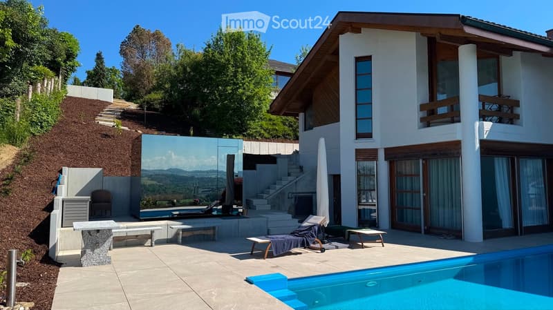 Modern outdoor area with a swimming pool, lounge chairs, a table, and a scenic view of the landscape.