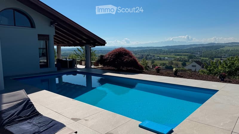 Outdoor area with a swimming pool, lounge chair, and scenic mountain view in the background.