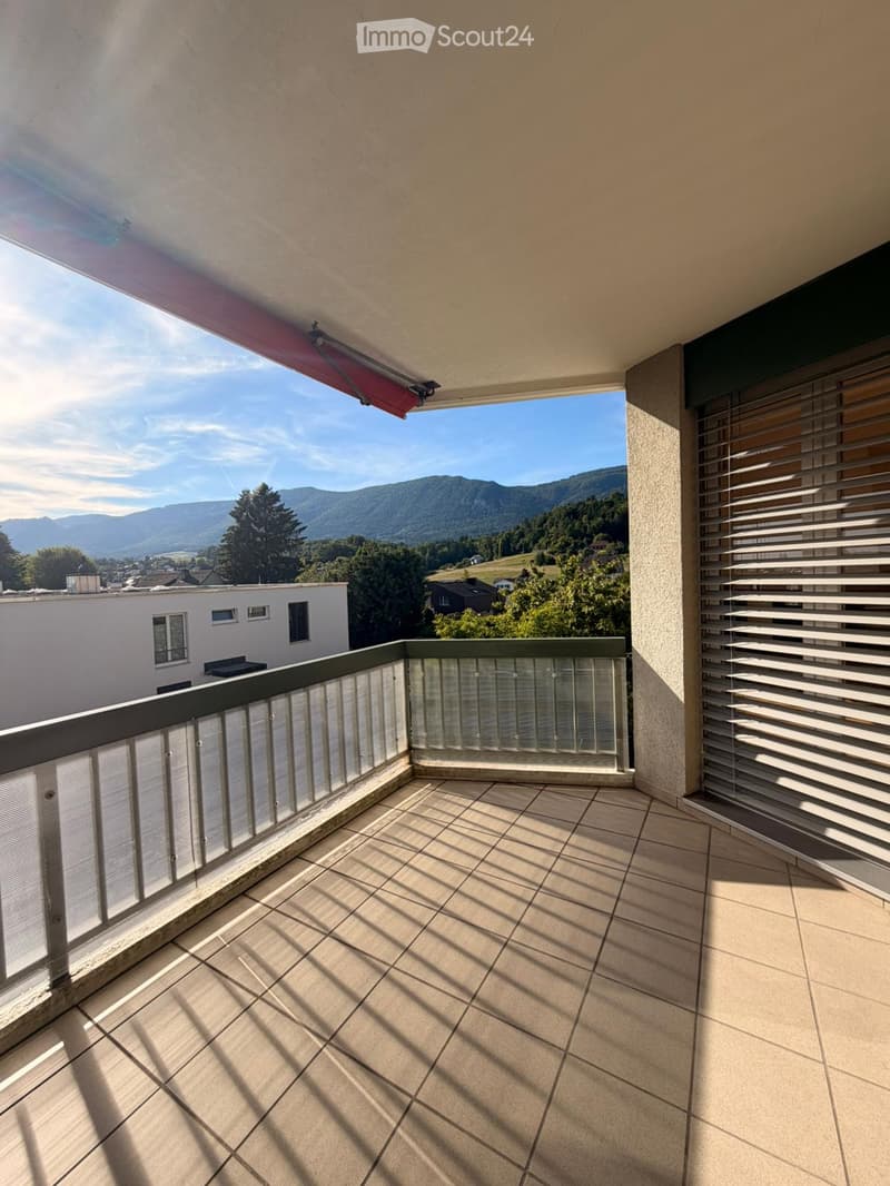 Balcony with tiled floor, glass railing, and scenic mountain view.