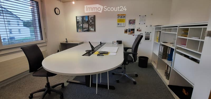 An empty office with large desk, shelves, trash bin, chairs, and clock on the wall.