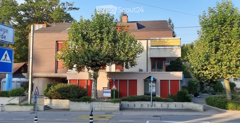 2 story building with red shutters, brick walls, windows, and shrubs
