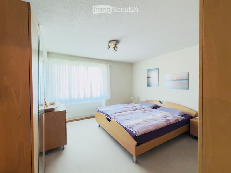 A well-lit bedroom with a double bed, nightstands, a lamp, and artwork on the wall.