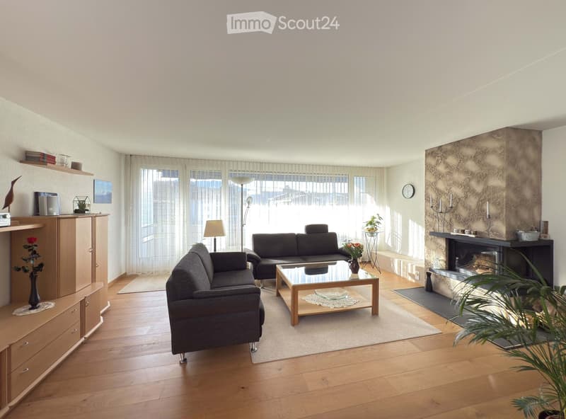 Bright living room with wooden flooring, fireplace, two sofas, coffee table, side table, and decorative items.